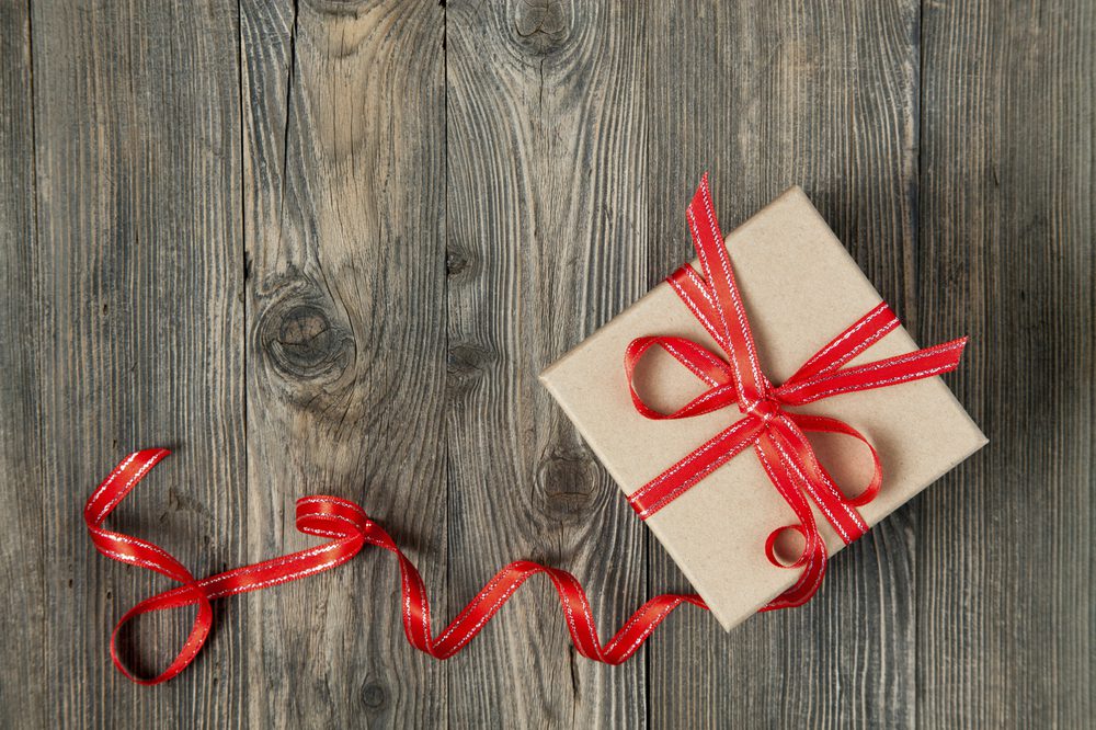 Gift box with red bow on wooden background